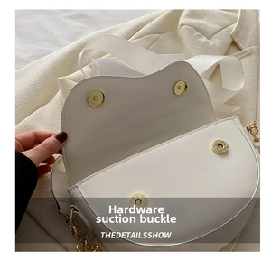 Gros plan de l'intérieur du sac selle blanc avec boucles aimantées dorées et bandoulière