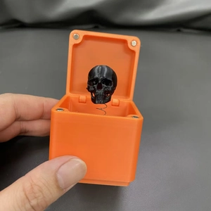 Scatola regalo scherzo arancione stampata in 3D con teschio nero nascosto su molla