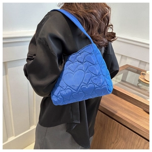 Sac hobo matelassé bleu à motifs cœurs porté par un mannequin en blouse satin
