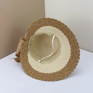 Detail eines zweifarbigen Strohhuts mit großer Sackleinen-Schleife und elastischem Windseil