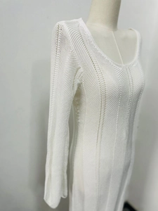 Detailed close-up of white knitted dress with vertical hollow-out patterns and V-neckline