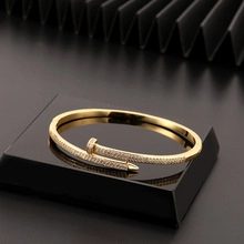 Dettaglio macro del bracciale a forma di chiodo placcato oro con pavé di zirconi