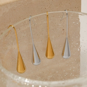 Minimalist gold and silver waterdrop earrings displayed on a glass with water droplets