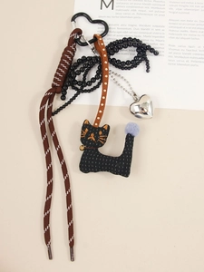 Detailed macro shot of a brown braided cord with black fabric cat and silver heart pendant