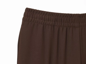 Gros plan sur la taille élastique et le tissu texturé de ce pantalon marron foncé fluide