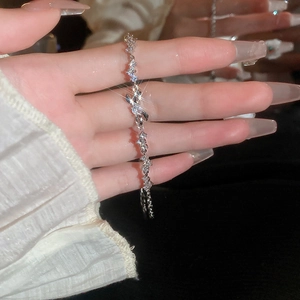Close-up of silver chain bracelet with zircon bunny charm on hand with black background