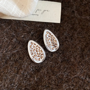 Detail of teardrop earrings with silver frames and leopard print on brown wool
