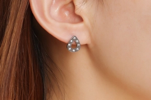 Macro shot of silver teardrop stud earrings with crystal inlay on model's ear