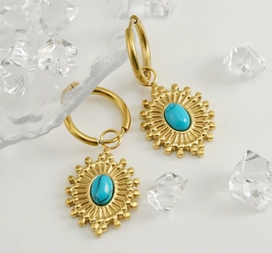 Détail de boucles d'oreilles bohèmes dorées avec motif tournesol et pierres turquoise