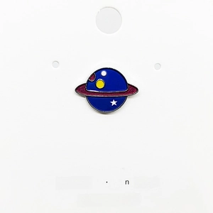 Detailed view of dark blue planet enamel pin with stars on white display card