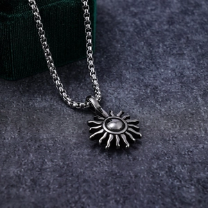 Retro stainless steel sun pendant necklace with silver box chain on dark stone surface