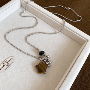 Detailed shot of star-shaped tiger eye stone pendant with silver fringe on snake chain