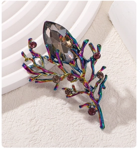 Macro shot of colorful branch brooch with large grey crystal and red rhinestones