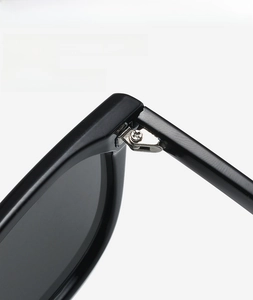 Detailed macro view of reinforced metal hinge and screws on black oversized sunglasses