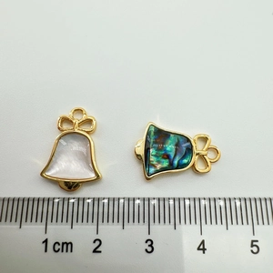 Detailed view of 18K gold plated bow bell charms in white shell and abalone shell material