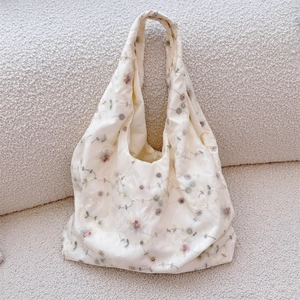 Detail of delicate floral embroidery on cream satin fabric of a women's tote bag