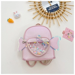 Detail of pink sequin schoolbag with heart-shaped transparent pocket and colorful wings