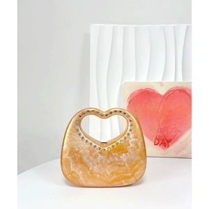 Detail of gold marble resin handbag featuring a rhinestone-studded heart shaped handle
