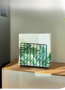 Zwarte metalen servethouder met bolvormige pootjes op een houten tafeloppervlak