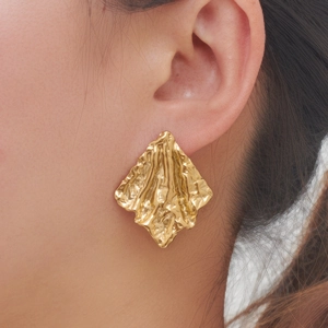 Macro view of gold irregular textured diamond earrings with hammered metal finish
