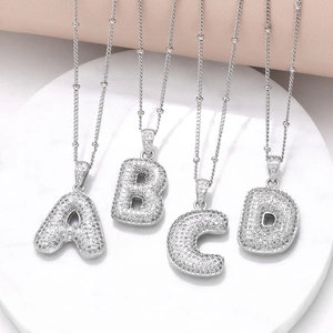 Silver A-D initial necklaces with zircon stones on a white marble display tray