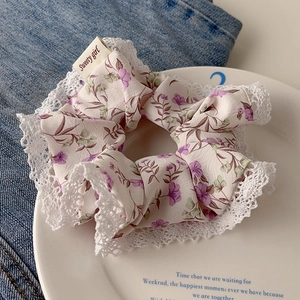 Close-up of floral scrunchie with lace edge and Sweety girl label on ceramic plate