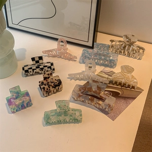 Flat lay of multiple acetate hair claws in checkered, marble, and tortoiseshell patterns