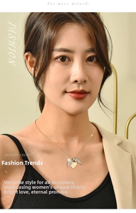 Detail of heart pendant with crystal wings on gold chain worn by a model