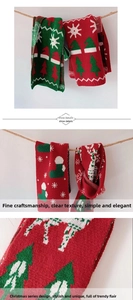 Detail of red and green Christmas knit scarf showing elk and tree patterns with thick texture