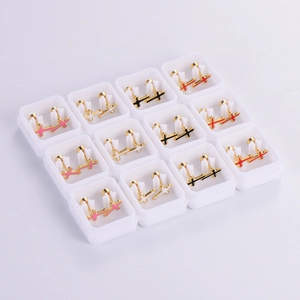 Macro shot of twelve pairs of gold metal cross stud earrings with colorful enamel filling