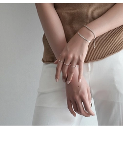 Macro detail of minimalist S925 silver rings and fine bracelets on model hand