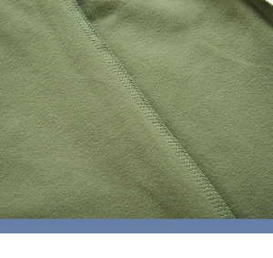 Gros plan du tissu de sweat olive montrant les détails de couture surjetée de qualité