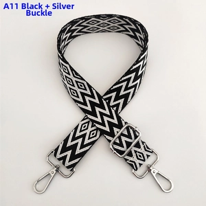 Detail of adjustable woven bag strap with black and white geometric wave patterns and silver metal hooks