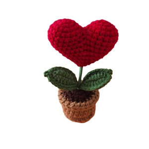 Handmade crochet red heart potted plant on desk with green leaves and brown base