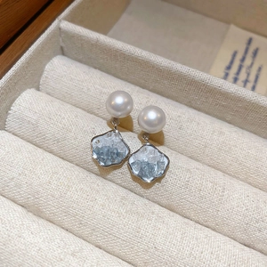 Close-up of butterfly earrings with silver needles, blue stones, and round white pearls