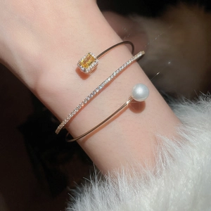 Detail of a three-layer gold bangle with zircon flowers, yellow gemstone and pearl