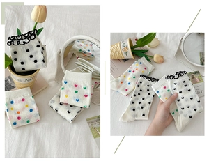 Close-up of white mesh mid-calf socks with polka dots, heart patterns and lace cuffs