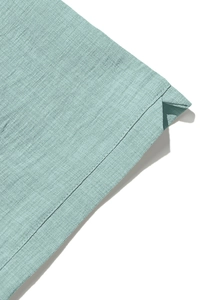 Macro detail of the light blue linen-textured shirt showing premium sewing craftsmanship