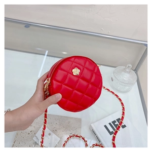Close-up of red quilted round crossbody bag with golden camellia and chain strap