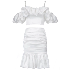 Detail of white satin two-piece set featuring pearl straps and ruffled crop top hem