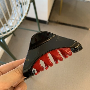 Detail of a two-tone black and red triangle hair claw clip in a glossy plastic finish