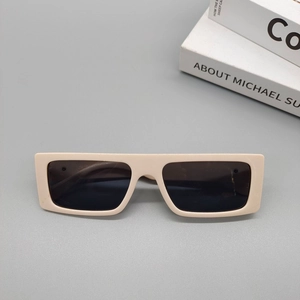 Flat lay of cream rectangle sunglasses with dark lenses on a minimalist grey background