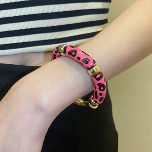 Gros plan sur bracelet en acrylique léopard rose avec perles intercalaires dorées