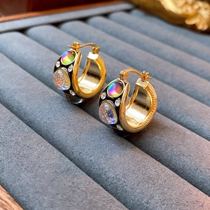 Macro shot of vintage gold earrings with black enamel and iridescent stones in detail