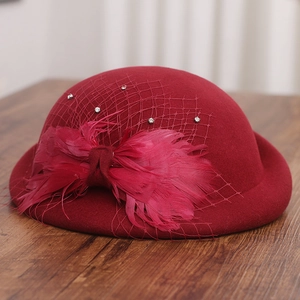 Detail of dark red wool beret with mesh veil, feather bow, and delicate rhinestones