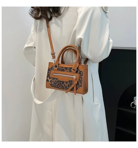 Detalle de bolso de mano con estampado de leopardo marrón y cremalleras decorativas plata