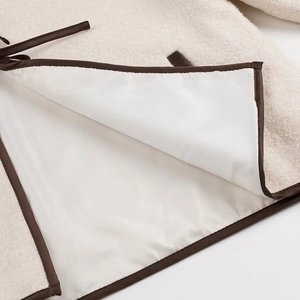 Detail of cream fuzzy fabric with dark brown leather piping and smooth white lining