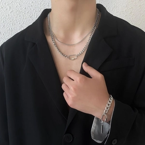 Detail shot of silver double-layer carabiner necklace and cuban bracelet on black suit