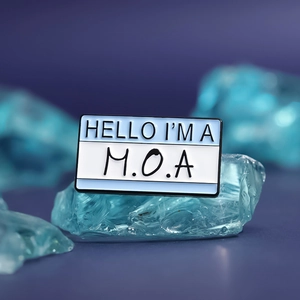 Hello My Name Is MOA creative enamel pin badge displayed on blue translucent crystals