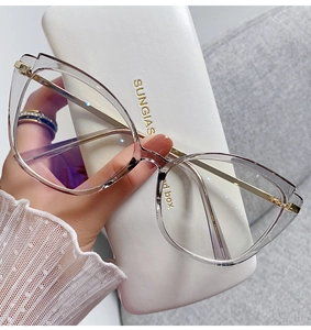 Detail of transparent tea cat-eye glasses with gold metal temples on a white case